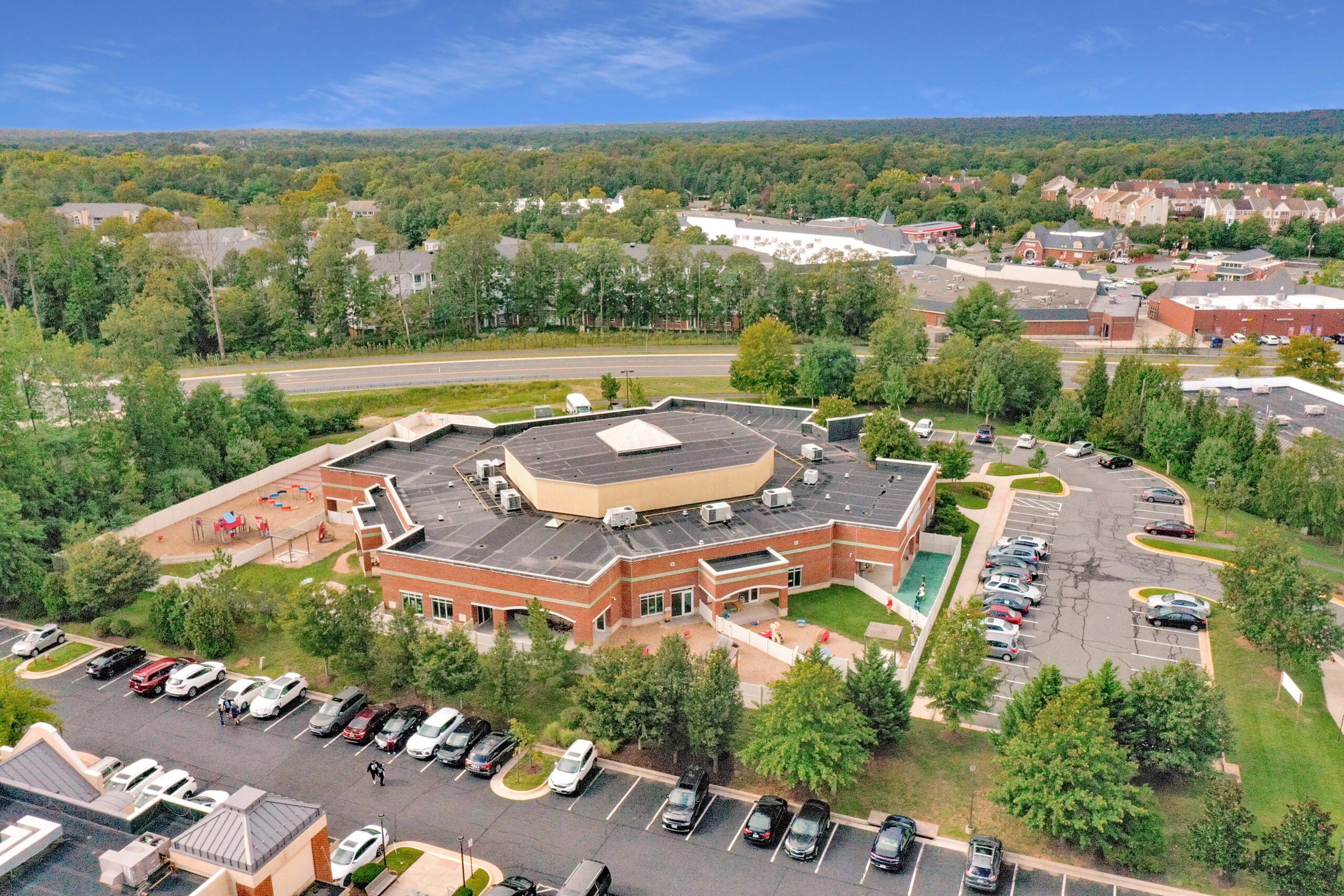 Aerial view of Kindercare Learning Center (formerly Creme de la Creme) in Fairfax County, Virginia, marketed by Serafin Real Estate, showing the facility's unique architecture, playground, and surrounding landscape.