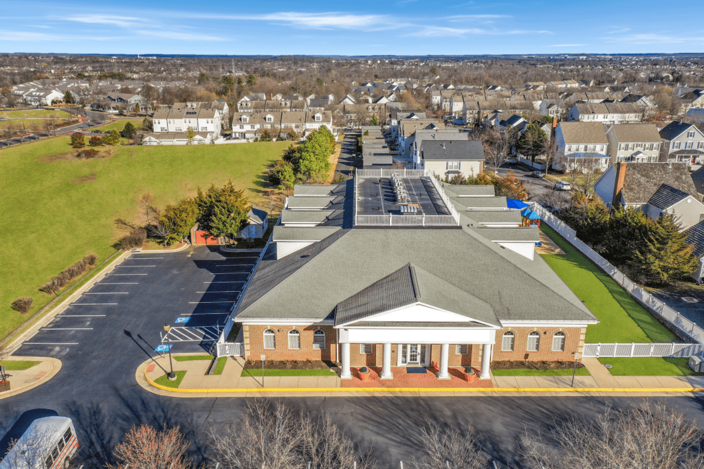 Aerial view of the early education center at 42885 Orchard Oriole Drive in Ashburn, VA, featuring a spacious parking lot, modern playground, and a well-maintained building in the Belmont Greene community